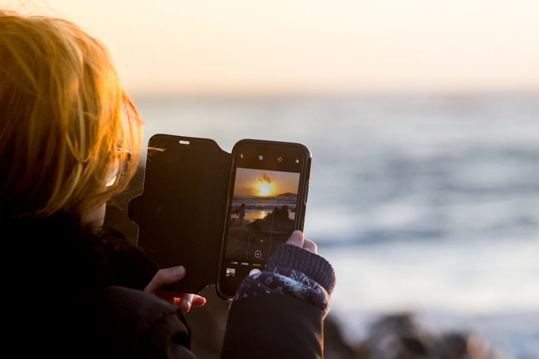 A girl filming the sunset on her phone