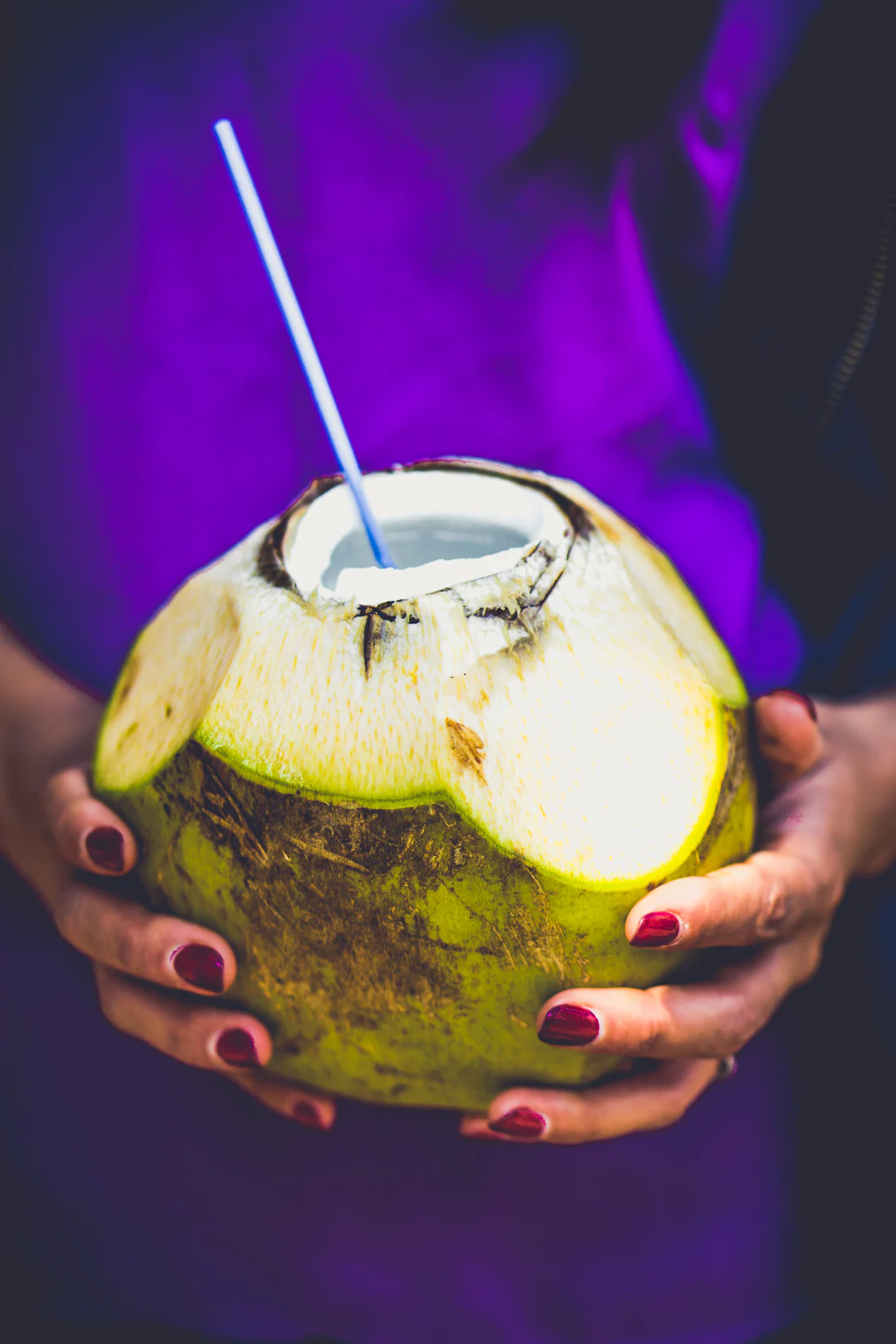 A coconut with a straw in hand
