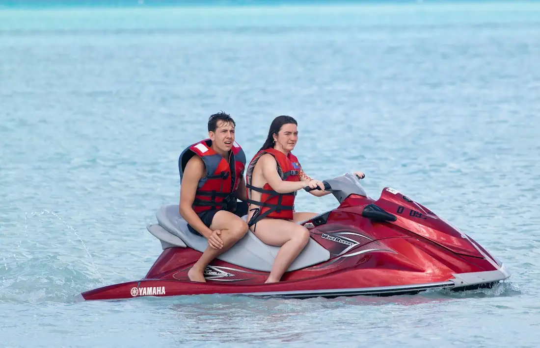 A couple on a red jet ski in clear water