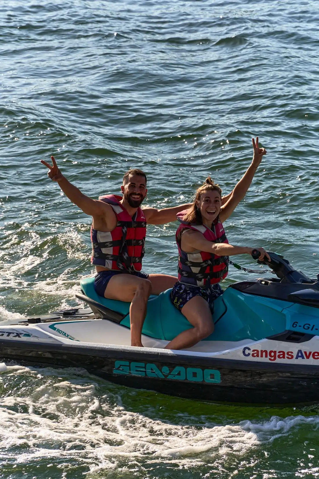 A couple on a jet ski joyfully raising their arms