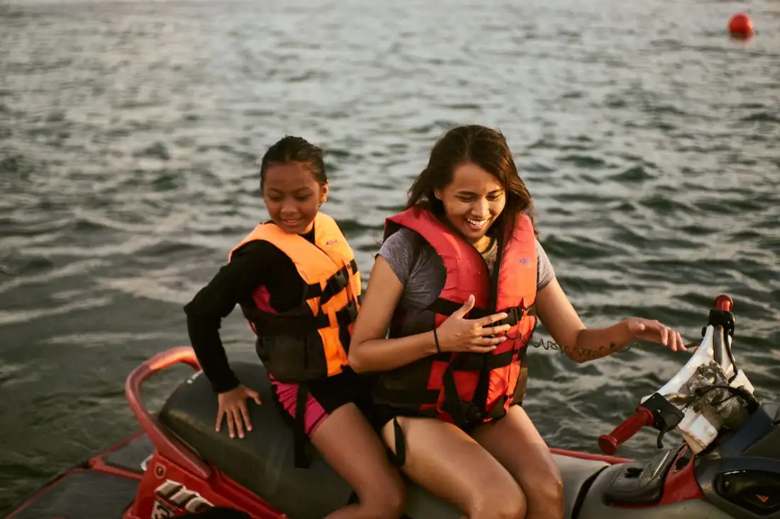 A mother and daughter laughing on a jet ski