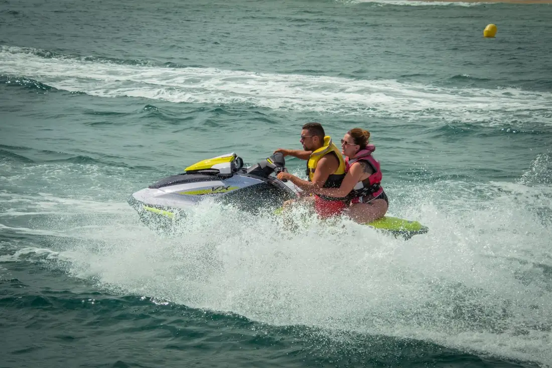 A couple on a jet ski in a cloud of spray